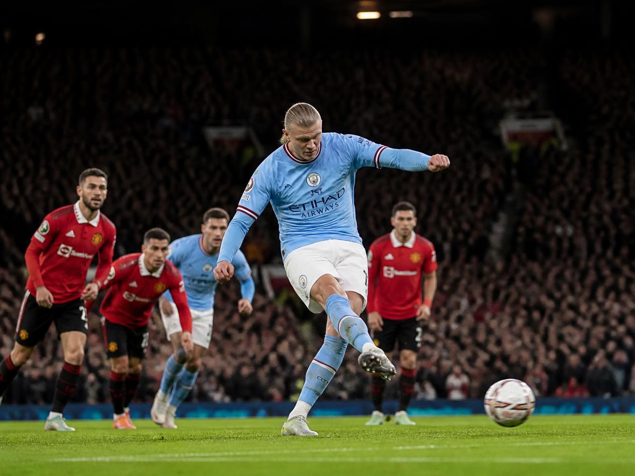 Premier League striker shooting at goal in front of a packed stand