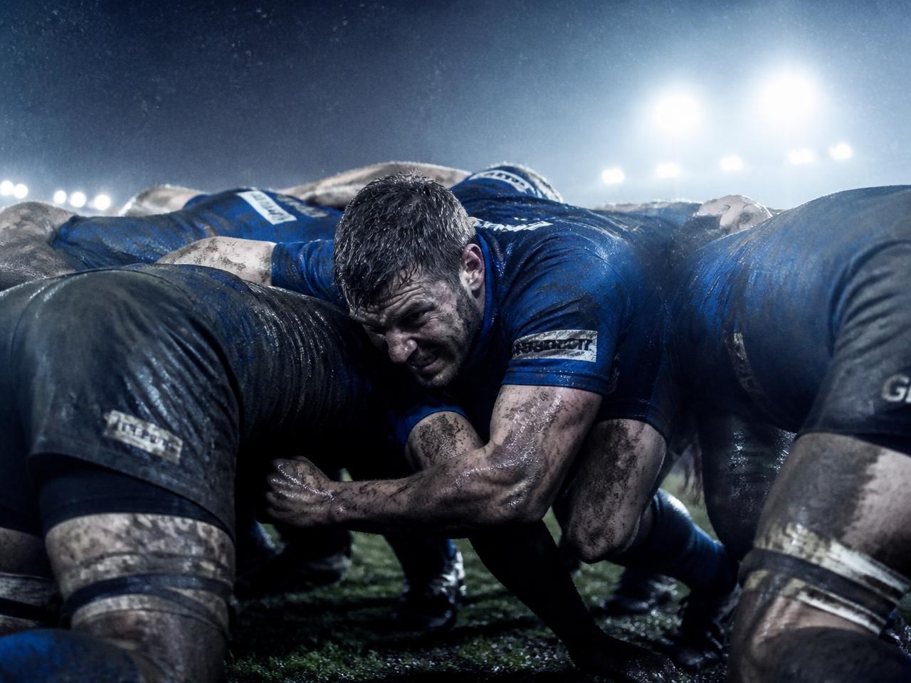 Players locked together on a wet floodlit pitch